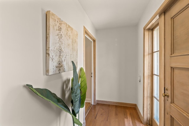 corridor featuring baseboards and light wood-style flooring