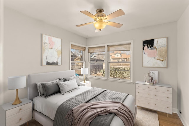 bedroom with a ceiling fan, baseboards, and light wood-style floors