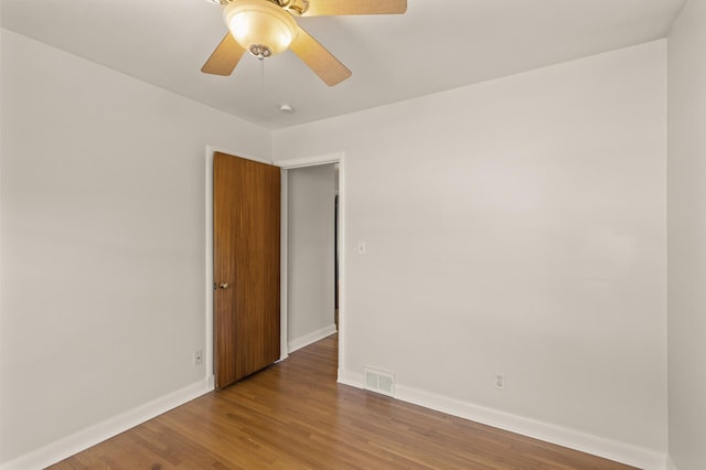 empty room featuring baseboards, visible vents, ceiling fan, and wood finished floors