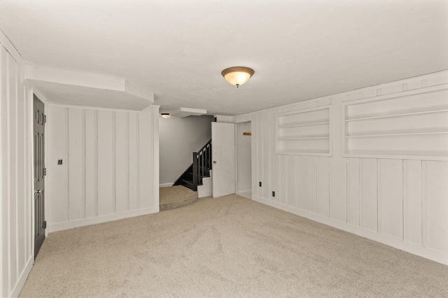 finished basement with stairway, built in features, and carpet