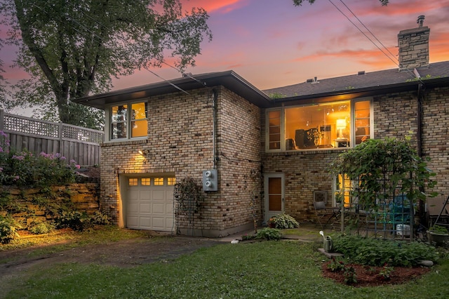 view of front of house with fence, an attached garage, a chimney, and brick siding