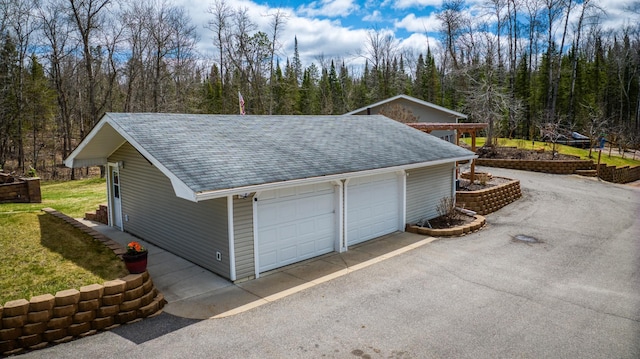 detached garage featuring a view of trees
