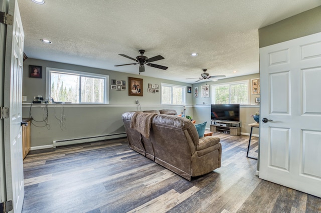 living area with a textured ceiling, wood finished floors, a ceiling fan, and a baseboard heating unit