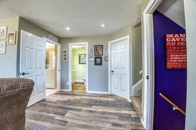 corridor featuring a textured ceiling, wood finished floors, baseboards, and recessed lighting