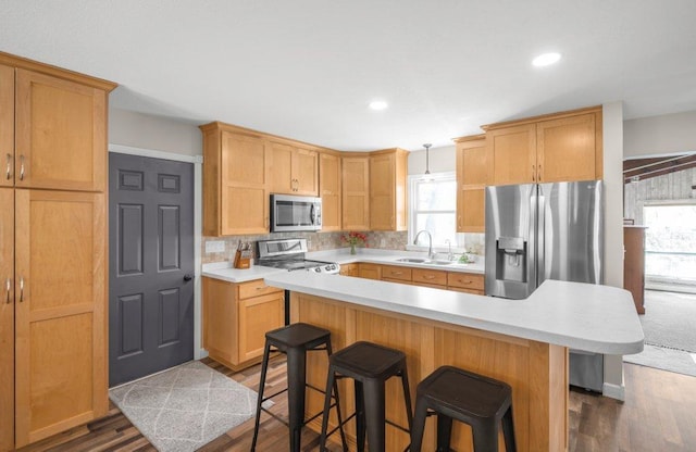 956 10th Ave SE, Forest Lake, MN 55025 - kitchen with stainless steel appliances, a sink, a breakfast bar, light countertops, and dark wood finished floors