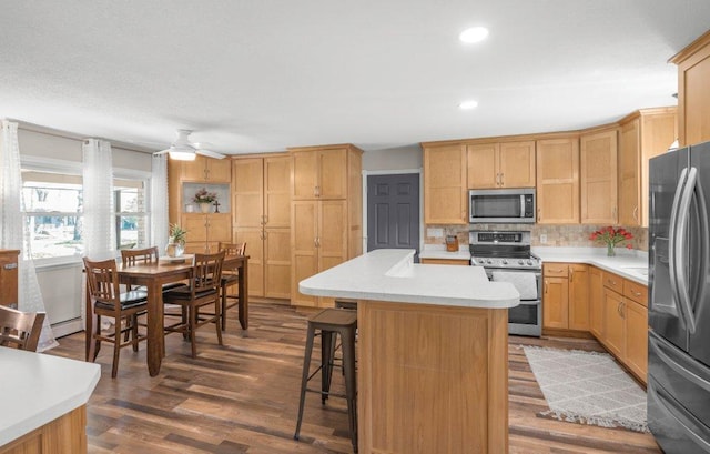 956 10th Ave SE, Forest Lake, MN 55025 - kitchen featuring appliances with stainless steel finishes, light countertops, backsplash, a center island, and a breakfast bar area