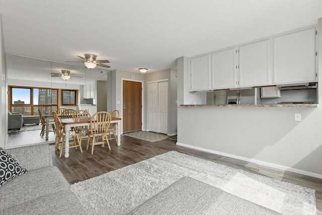 dining room with baseboards, ceiling fan, and dark wood-style floors