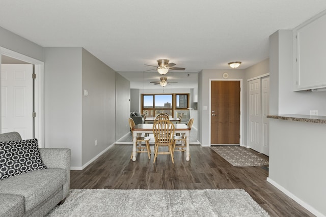 dining area with baseboards, ceiling fan, and dark wood-style floors