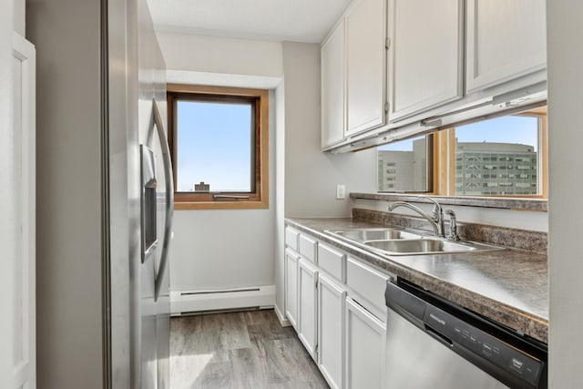 kitchen featuring a baseboard radiator, a sink, white cabinetry, and stainless steel appliances