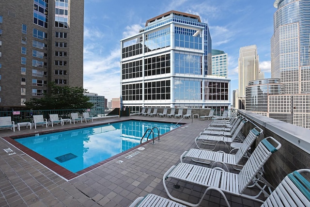 pool featuring fence, a view of city, and a patio