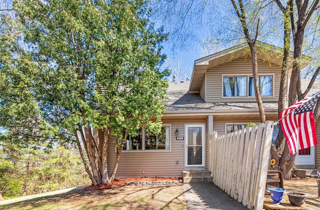 rear view of property with roof with shingles and entry steps