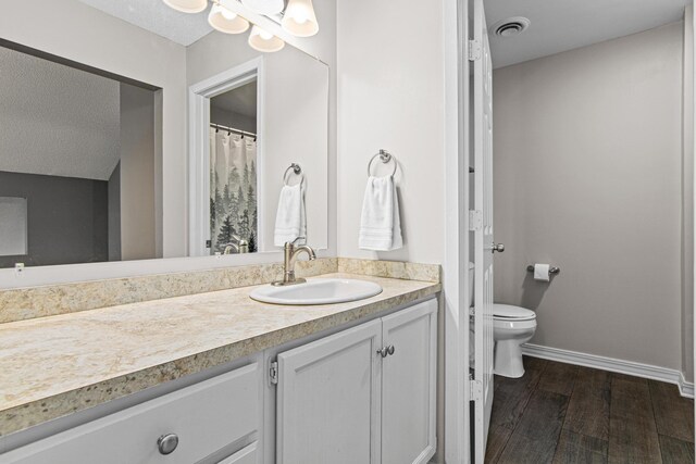 full bathroom with visible vents, wood finished floors, vanity, baseboards, and toilet