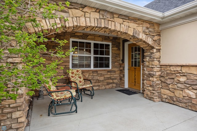 property entrance with stone siding and roof with shingles