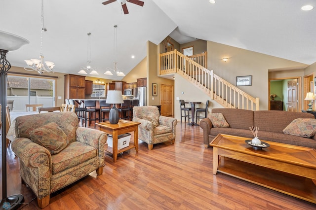 living room featuring stairway, a chandelier, light wood-type flooring, ceiling fan, and high vaulted ceiling