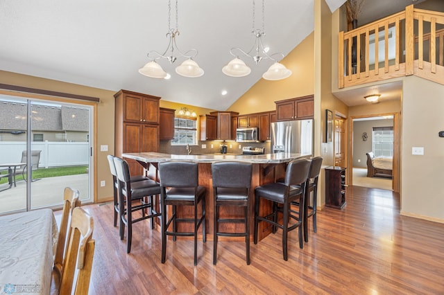 kitchen with stainless steel appliances, light wood-type flooring, a chandelier, a center island, and a kitchen breakfast bar