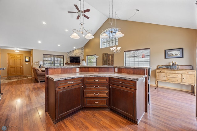 kitchen featuring high vaulted ceiling, open floor plan, a ceiling fan, dark wood-style flooring, and light stone countertops