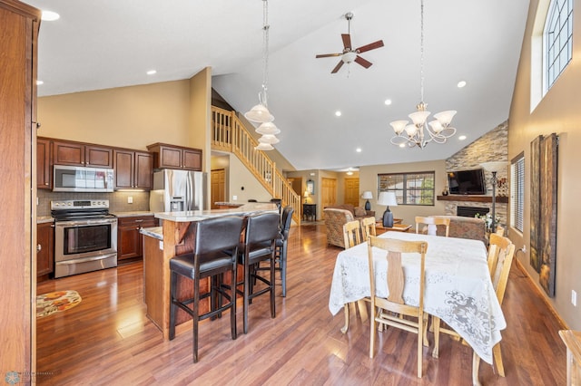 dining room with high vaulted ceiling, stairs, wood finished floors, a chandelier, and recessed lighting
