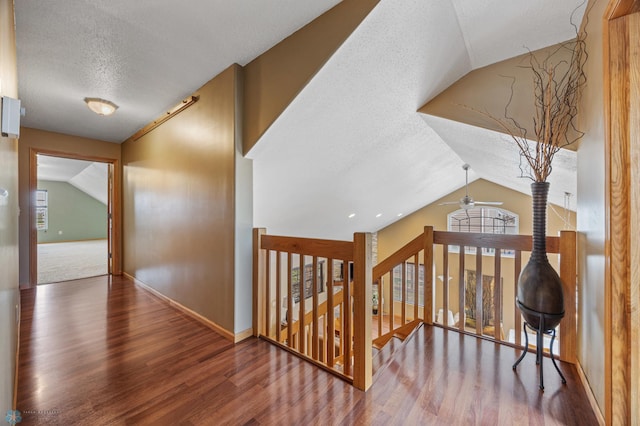 corridor featuring lofted ceiling, a textured ceiling, wood finished floors, plenty of natural light, and baseboards