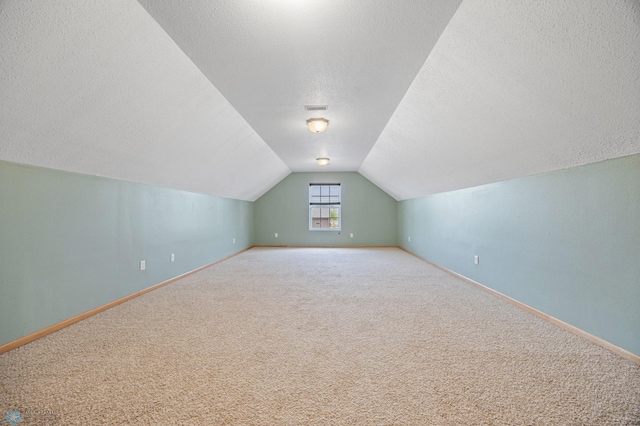 bonus room with a textured ceiling, carpet flooring, lofted ceiling, and baseboards