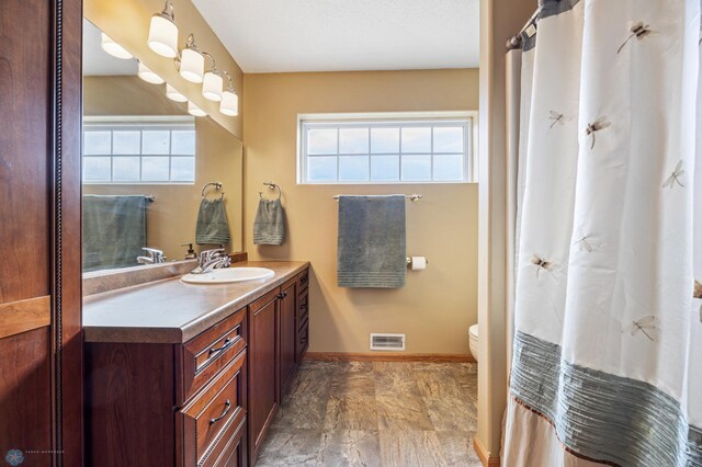 bathroom featuring toilet, vanity, and baseboards
