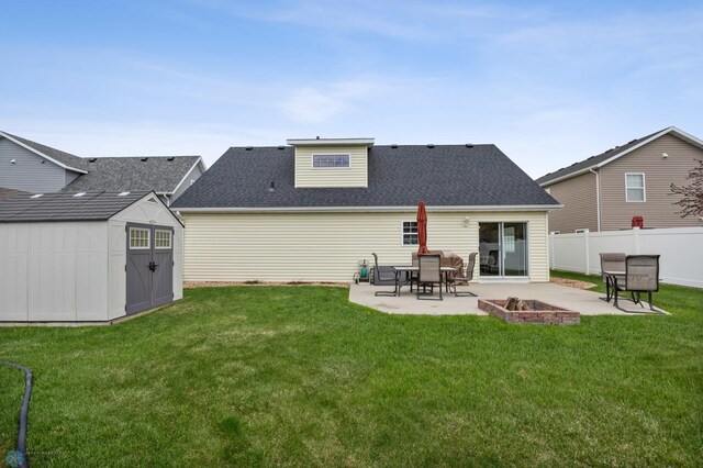 back of property featuring a patio, a shed, an outbuilding, roof with shingles, and an outdoor fire pit