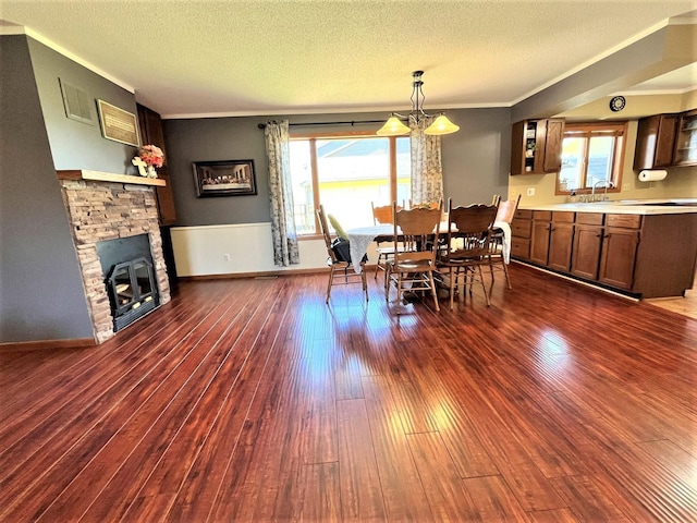 dining room with ornamental molding, dark wood-style floors, a fireplace, healthy amount of natural light, and a textured ceiling