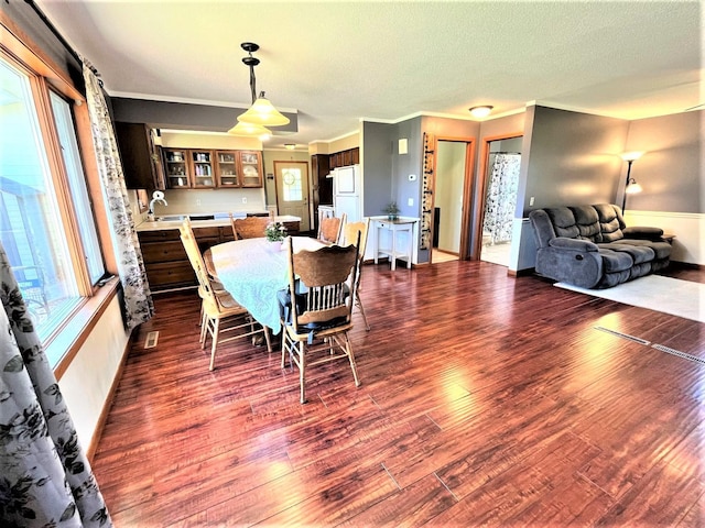 dining space featuring dark wood-style floors, crown molding, baseboards, and a textured ceiling