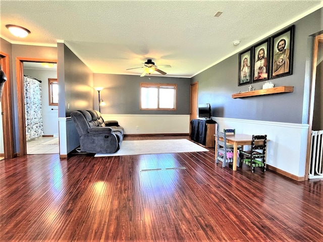 living area with wood finished floors, a ceiling fan, a textured ceiling, and radiator heating unit