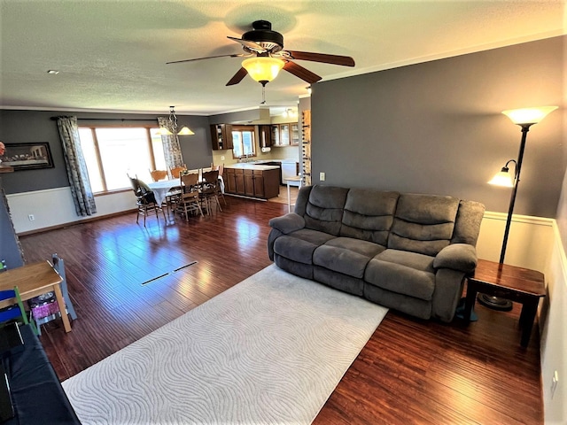 living area with dark wood-style flooring, ceiling fan, and ornamental molding