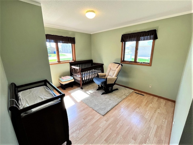 bedroom featuring ornamental molding, wood finished floors, a textured ceiling, and baseboards