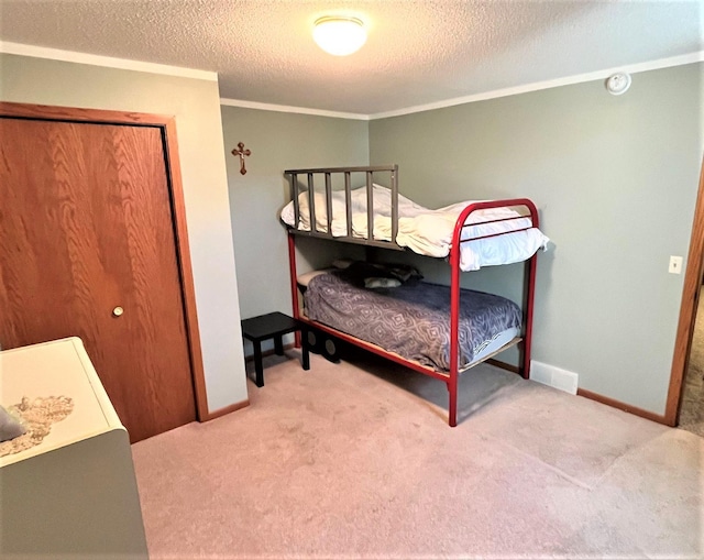 bedroom with carpet floors, a textured ceiling, ornamental molding, and baseboards