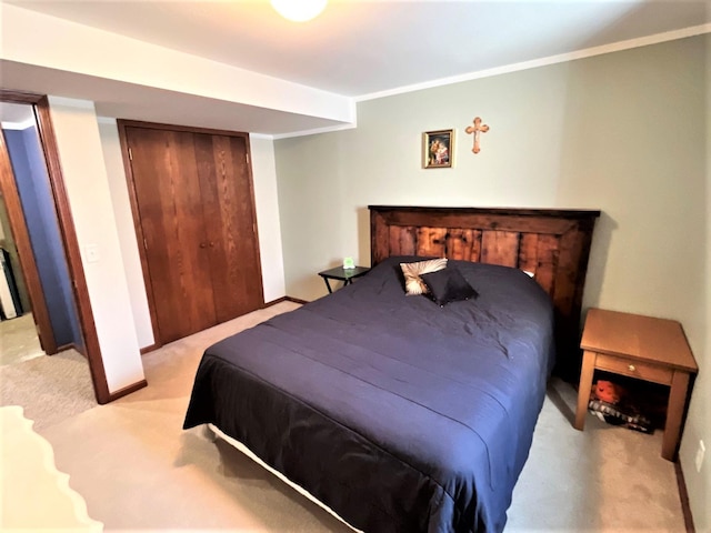 bedroom featuring light carpet, crown molding, baseboards, and a closet