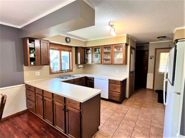kitchen featuring white appliances, a peninsula, a sink, a textured ceiling, and light countertops