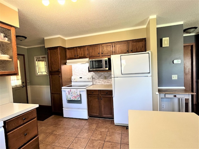 kitchen with white appliances, under cabinet range hood, a textured ceiling, light countertops, and decorative backsplash