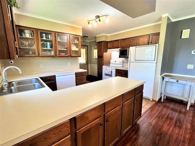 kitchen featuring white appliances, a sink, light countertops, glass insert cabinets, and dark wood-style flooring