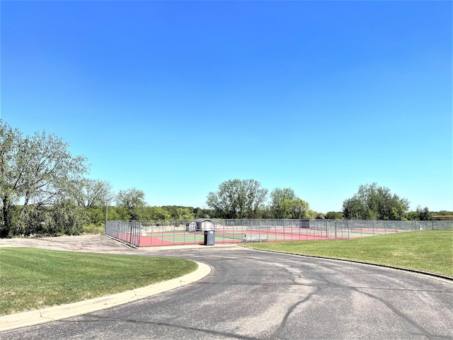 view of asphalt road with curbs and a gate