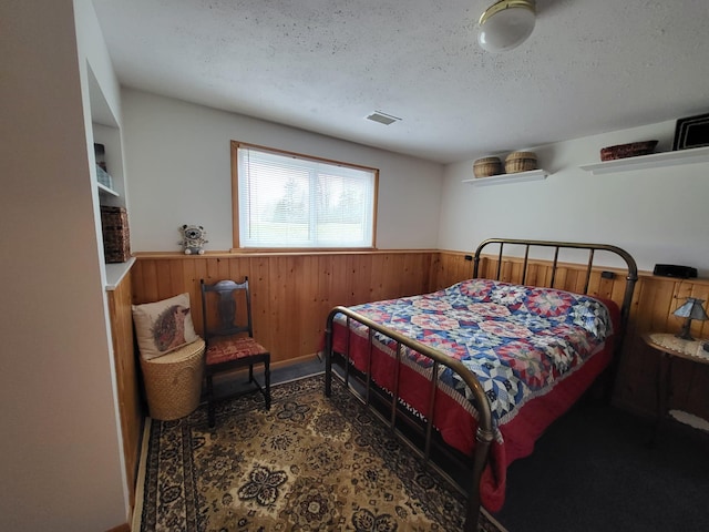 5344 Shady Ln, Canosia Twp, MN 55811 - bedroom featuring wood walls, wainscoting, visible vents, and a textured ceiling