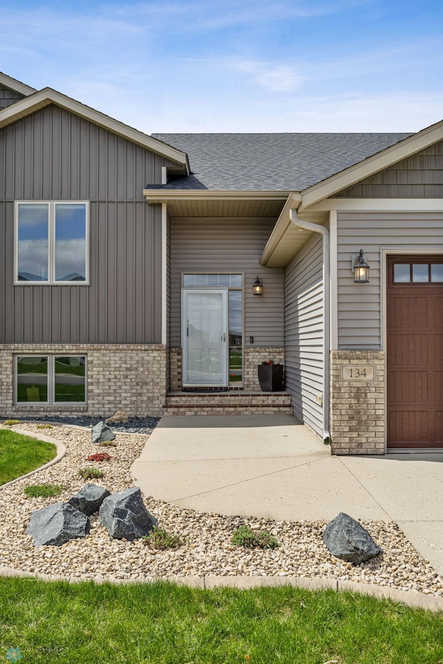 134 Newport Pkwy N, Kindred, ND 58051 - property entrance with roof with shingles, an attached garage, brick siding, and board and batten siding