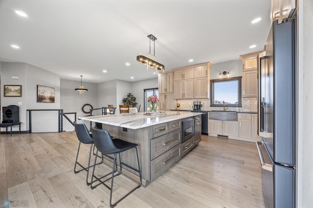 134 Newport Pkwy N, Kindred, ND 58051 - kitchen with light wood finished floors, refrigerator, light brown cabinetry, a breakfast bar, and black microwave