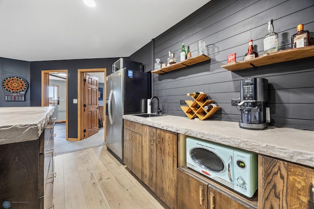 134 Newport Pkwy N, Kindred, ND 58051 - kitchen with light wood-style flooring, a sink, open shelves, brown cabinetry, and stainless steel refrigerator with ice dispenser