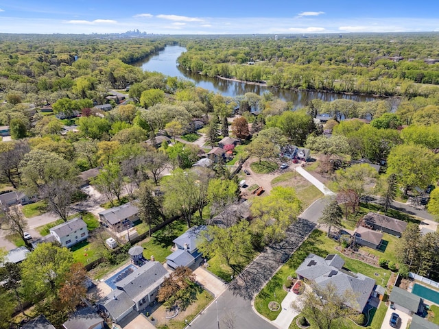 aerial view of property's location featuring a nearby body of water and a forest