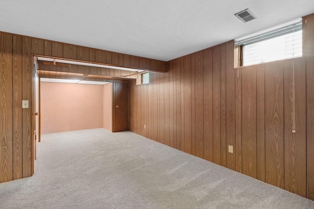 basement with carpet, wooden walls, and healthy amount of natural light