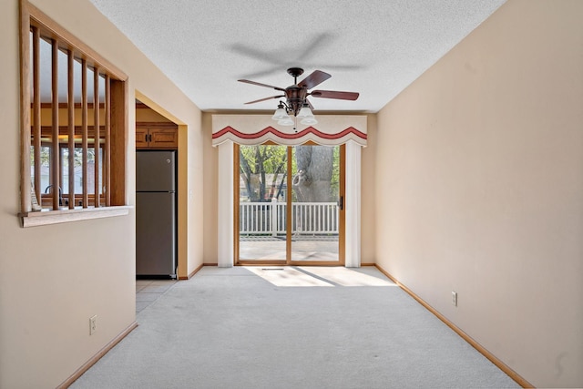 spare room featuring a ceiling fan, light carpet, a textured ceiling, and baseboards