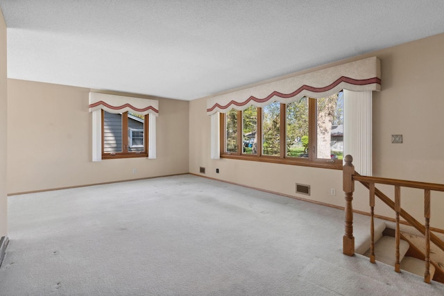 unfurnished room with carpet, a textured ceiling, and baseboards