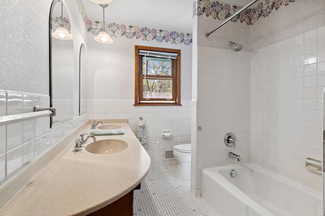 full bathroom with shower / tub combination, toilet, tile patterned floors, tile walls, and double vanity