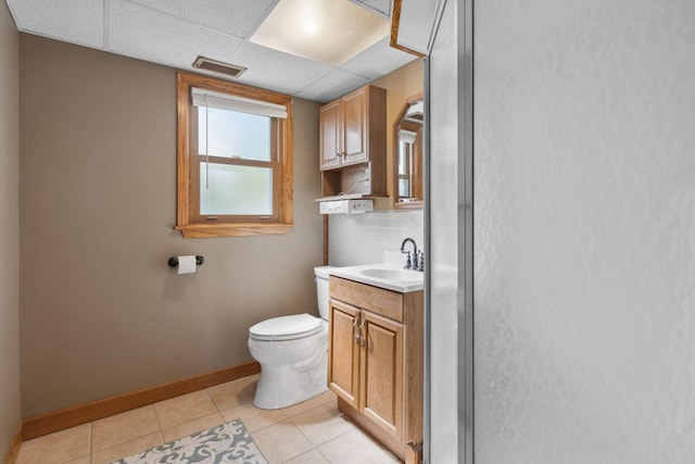 bathroom featuring toilet, tile patterned floors, vanity, baseboards, and backsplash