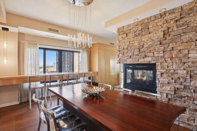 1235 Yale Pl Unit 1706, Minneapolis, MN 55403 - dining space featuring a textured ceiling, visible vents, a stone fireplace, and wood finished floors