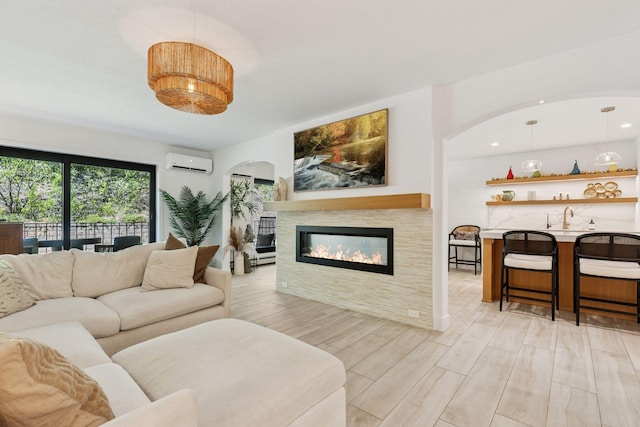 215 Barry Ave S Unit 116And 114, Wayzata, MN 55391 - living room with a wall unit AC, a glass covered fireplace, light wood-style flooring, and arched walkways
