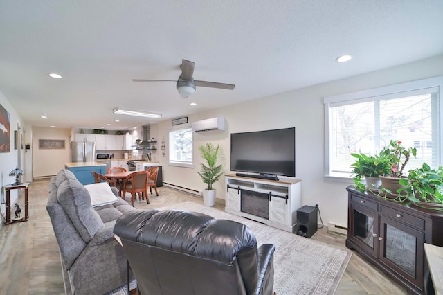 living area featuring a wall mounted air conditioner, light wood-style flooring, a ceiling fan, and a baseboard heating unit