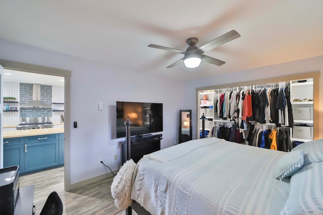 bedroom featuring a closet, baseboards, ceiling fan, light wood finished floors, and ensuite bath
